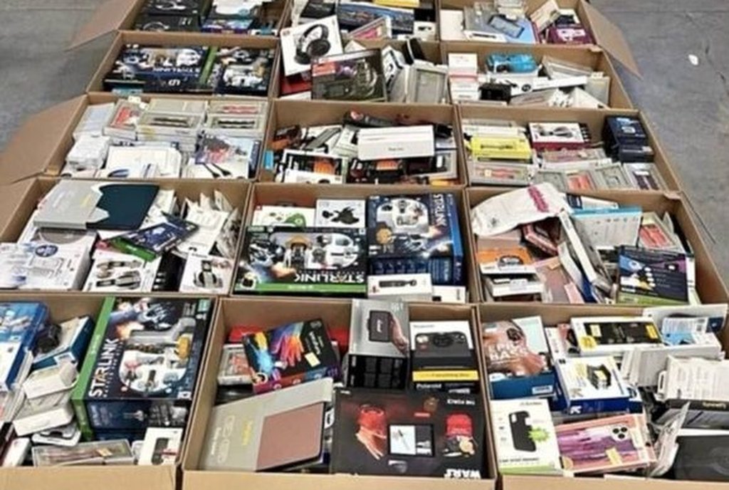 Várias caixas de papelão abertas lado a lado, cheias de pequenos eletrônicos e acessórios lacrados
