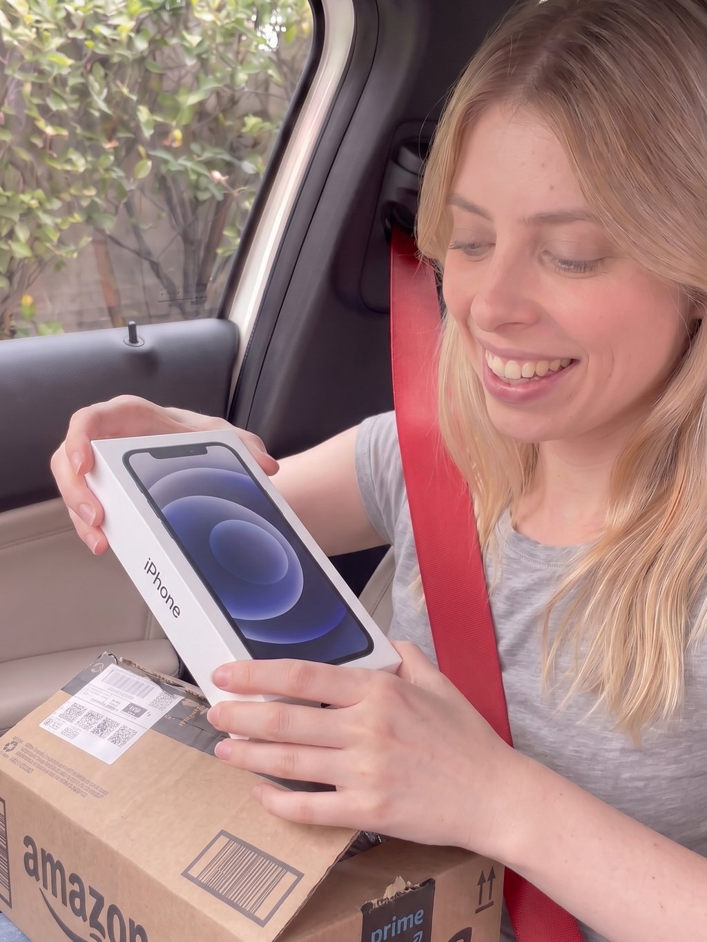 Cliente dentro do carro segurando um celular lacrado que veio na caixa