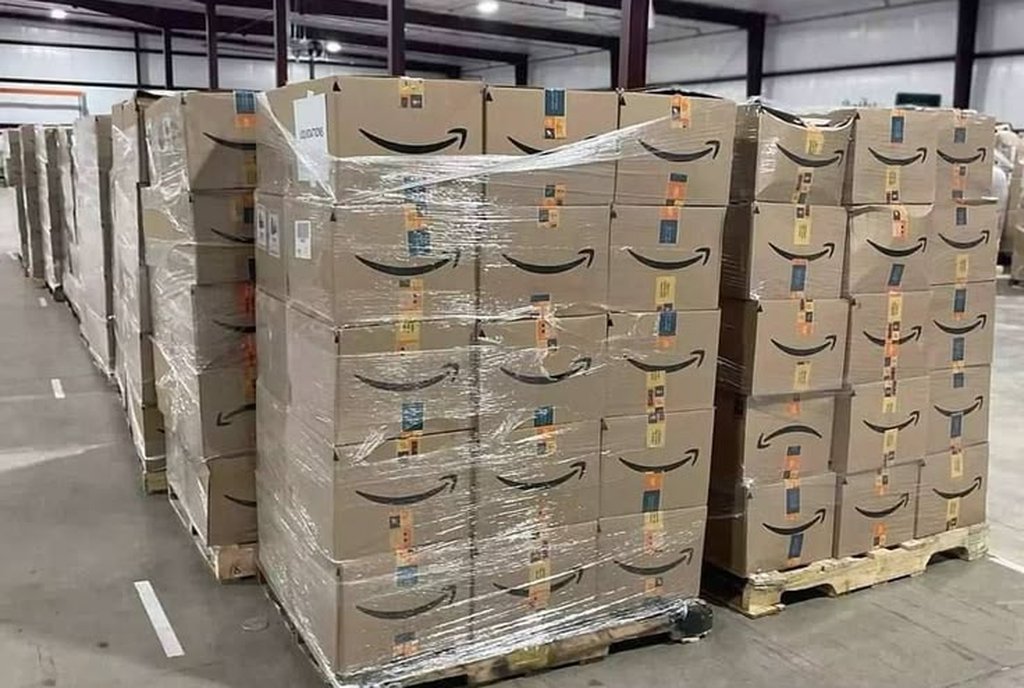 Fileira de paletes altos de caixas de papelão envelopadas em plástico dentro de um armazém